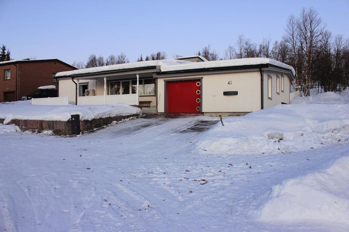 A building with a red garage door, a covered porch, and a number '41' on the side.
