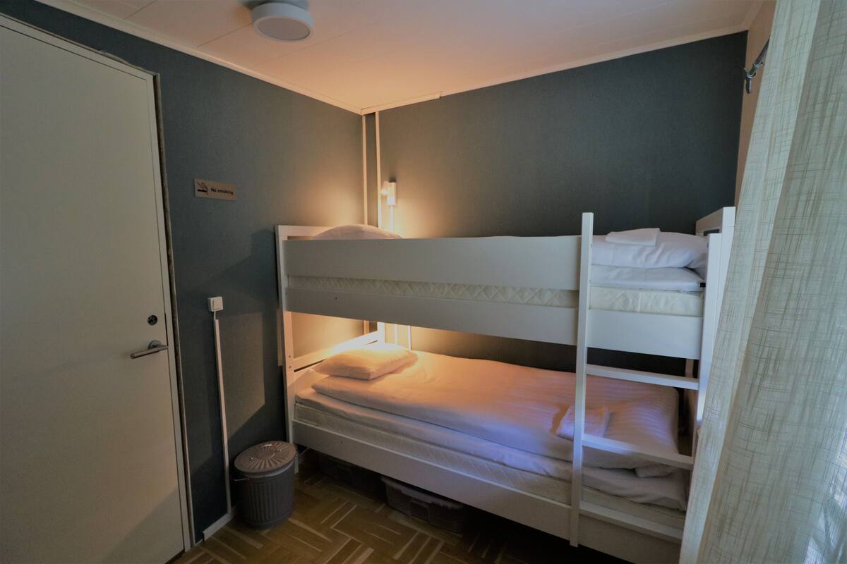 Habitación con literas, un letrero que dice 'No Fumar', un basurero y una puerta.