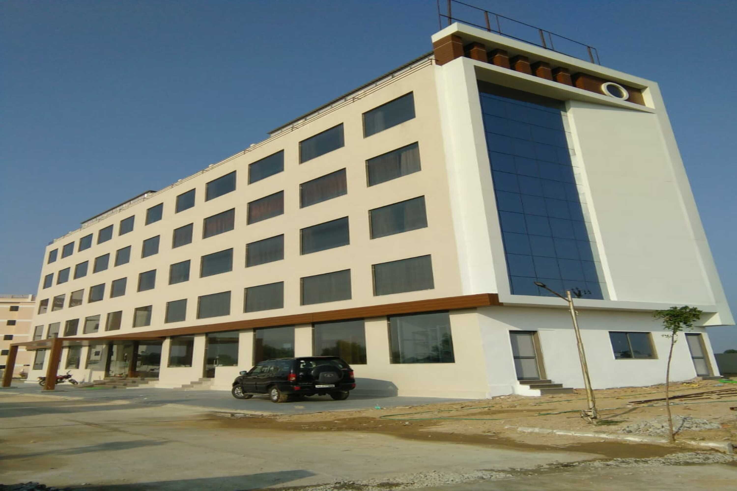 A multi-story hotel with a modern design, featuring a large glass facade on one side and a series of windows on the other.
