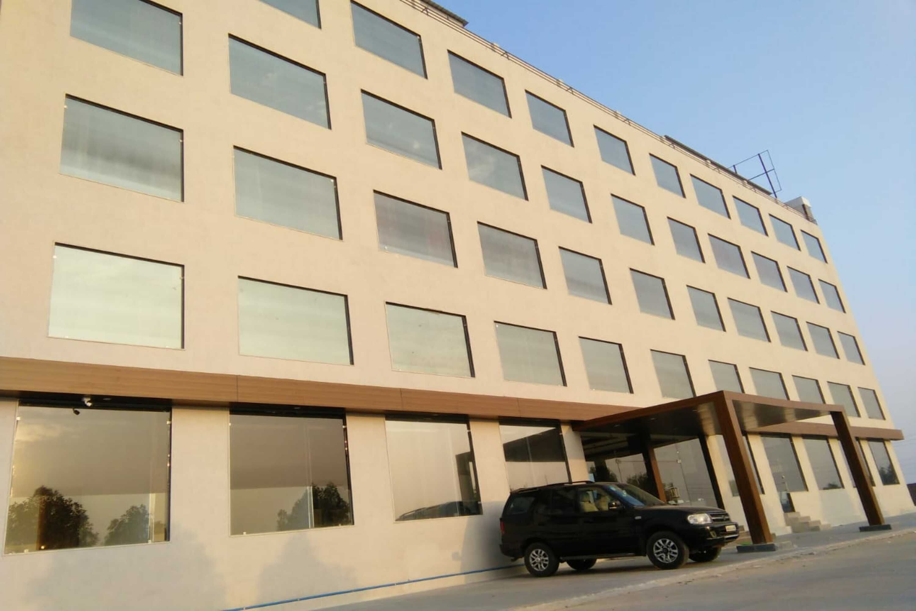 Un hotel de varios pisos con una fachada moderna, amplios ventanales y una zona de acceso cubierta.