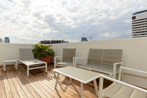 A rooftop terrace with white furniture, including a table and chairs, and a potted plant. - Duplex 2 bedroom with a terrace (Tel Aviv)