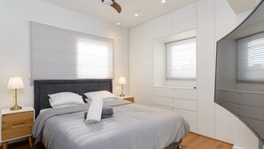 Une chambre à coucher moderne avec un lit, des lampes de chevet et un ventilateur de plafond.