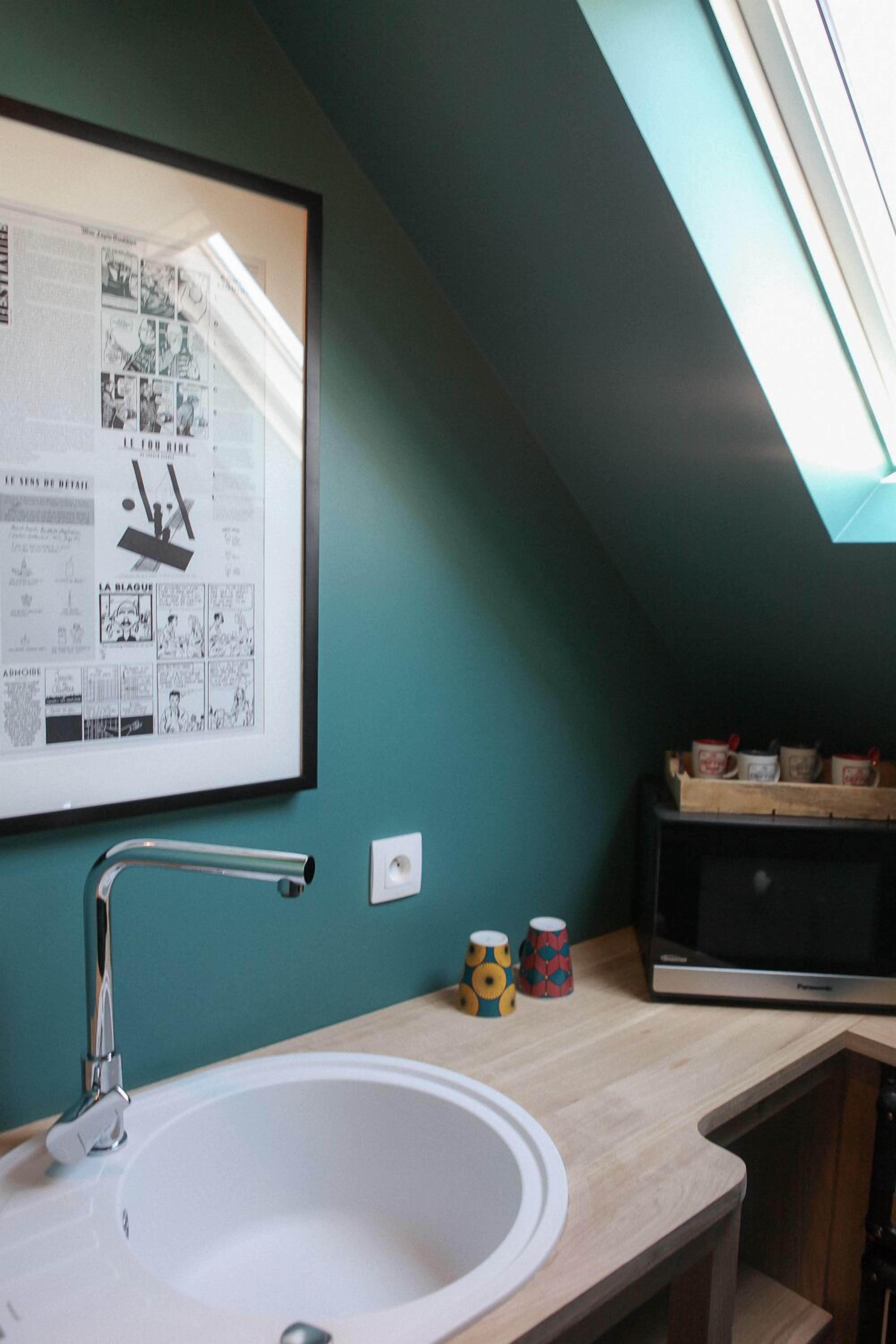 A kitchen with a white sink, a framed newspaper, and a microwave on a wooden countertop.