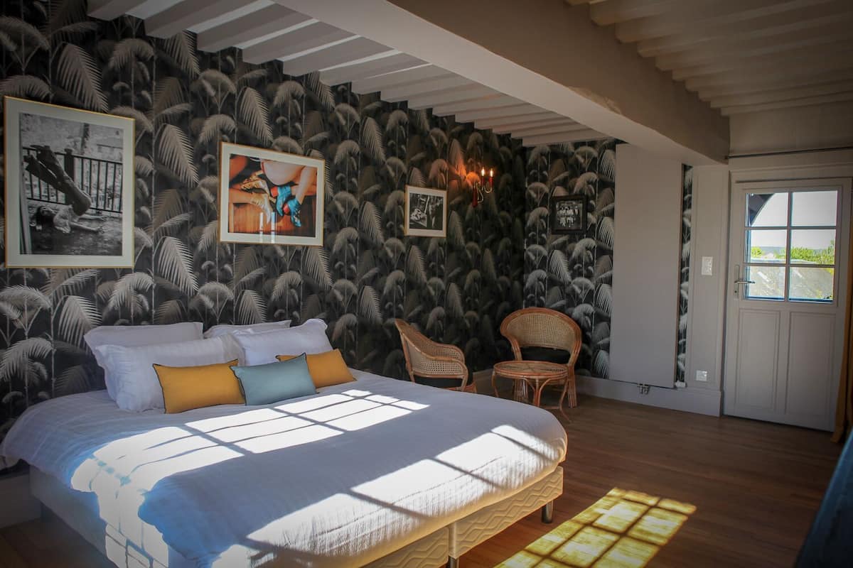 Ein Schlafzimmer mit einem Bett, zwei Stühlen, einer Tür und einer Wand mit dekorativer Tapete.