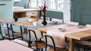 A dining area with a wooden table, chairs, and a vintage-style chandelier. - Le Manoir des Chevaux Dorés (Le Neubourg)