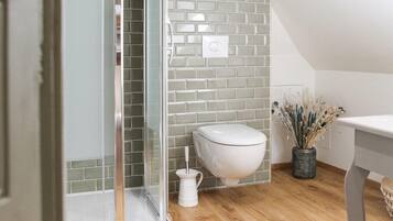 A modern bathroom with a glass shower enclosure, a white toilet, and a wooden floor.