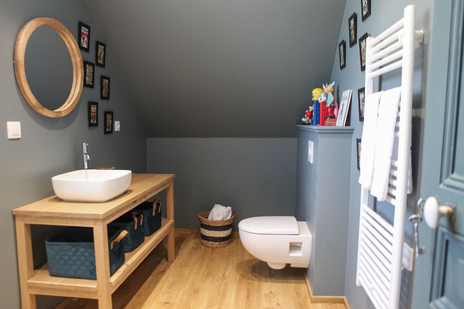 A bathroom with a wooden vanity, a white sink, a toilet, and a towel rack.