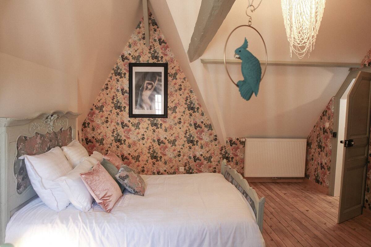 Ein Schlafzimmer mit einem Bett, einem gerahmten Bild an der Wand und einer vogelartigen Dekoration.