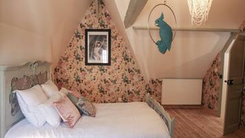 A bedroom with a bed, a framed picture on the wall, and a bird-shaped decoration.