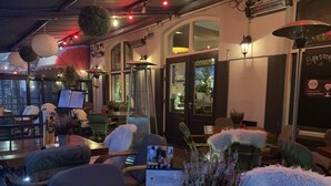 Un espace de détente intérieur avec des tables, des chaises et des plantes suspendues.