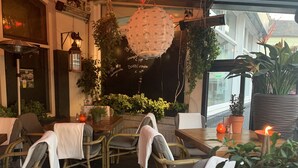 Un espace de restauration intérieur avec des chaises et des tables en osier, ainsi que des plantes en pot.
