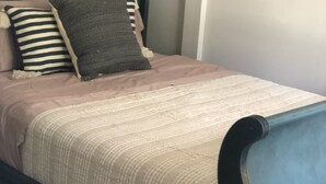 Una cama con cabecera oscura, almohada a rayas y manta color beige.