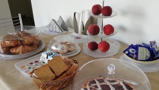 Ein Büfett mit verschiedenen Speisen, darunter Gebäck, Brot und einer abgedeckten Torte.