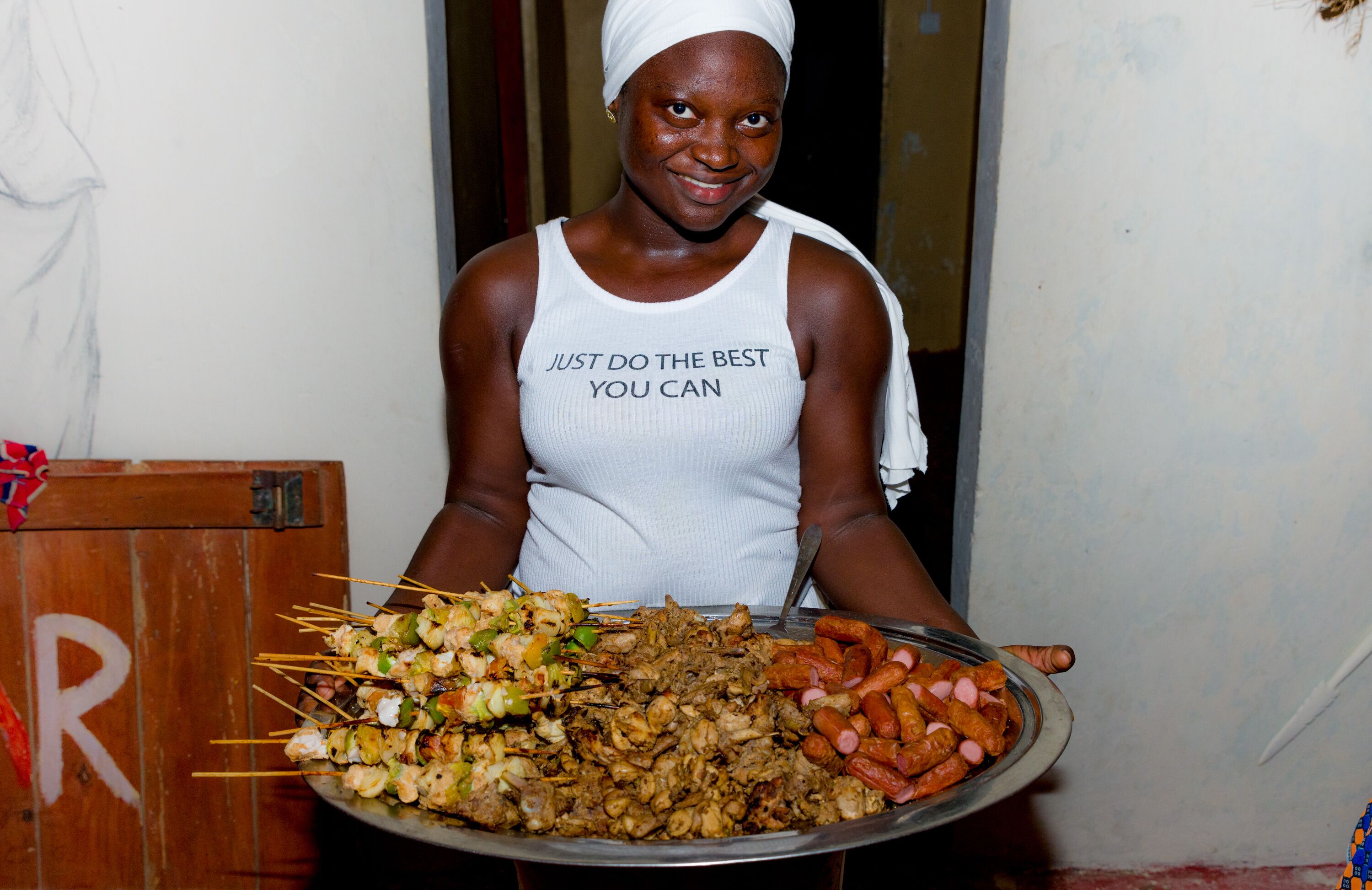 A person holding a large platter with various skewers and sausages.