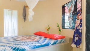 Un dormitorio con cama, ventana con cortinas e un equipo de aire acondicionado instalado en la pared.