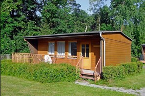 A wooden cabin with a porch, a door, and windows. - Ferienpark am Hellsee (Biesenthal)
