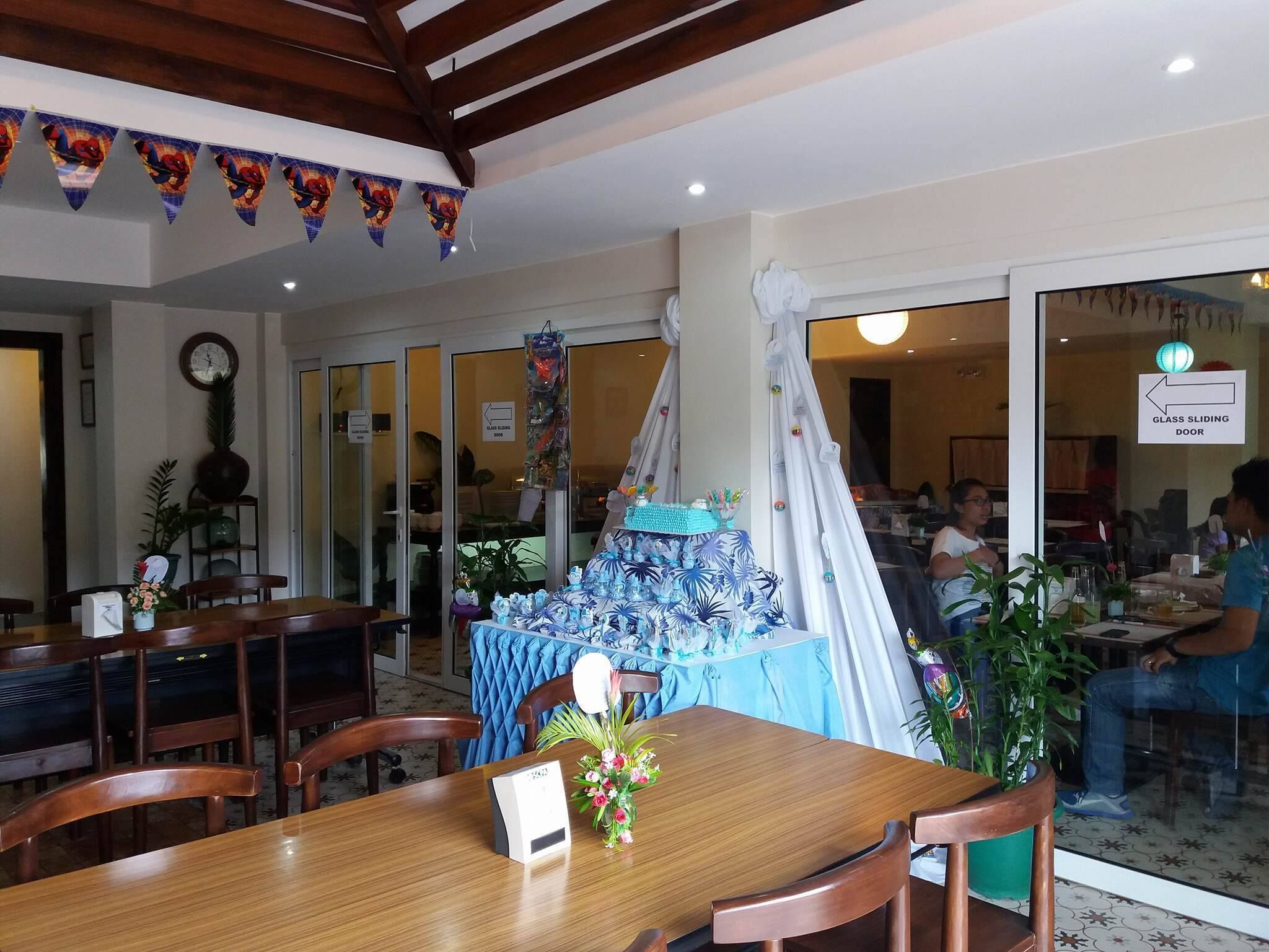 Een restaurant met een houten tafel en stoelen, een blauwe tafelkleed en een glazen schuifdeur.
