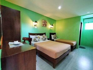 A hotel room with two beds, a wooden desk, and green walls. - Pension Ivatan (Basco)