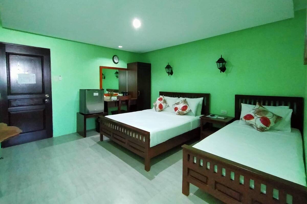 A room with two wooden beds, a desk, a chair, a wardrobe, and a door.