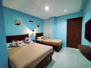 A room with two beds, a wooden door, and a wall-mounted TV. - Pension Ivatan (Basco)