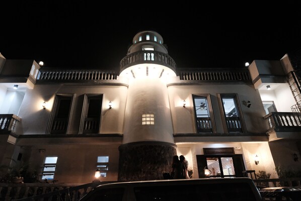 A historic building with a prominent central tower, large windows, and a well-lit entrance. - Pension Ivatan (Basco)