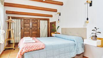 A bedroom with a bed, wooden wardrobe, and a hanging light fixture.