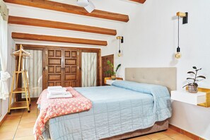 A bedroom with a bed, wooden wardrobe, and a hanging light fixture.