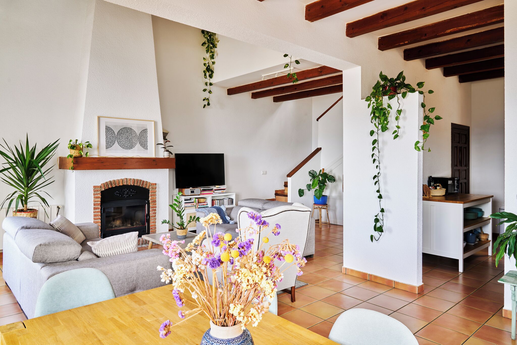A living room with a fireplace, sofa, coffee table, and a dining area with a table and chairs.