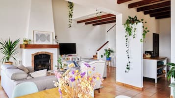 A living room with a fireplace, sofa, coffee table, and a dining area with a table and chairs.