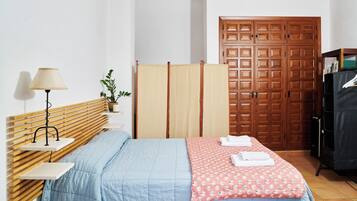 Un dormitorio con cama, mesita de noche, lámpara, planta, armario y closet.