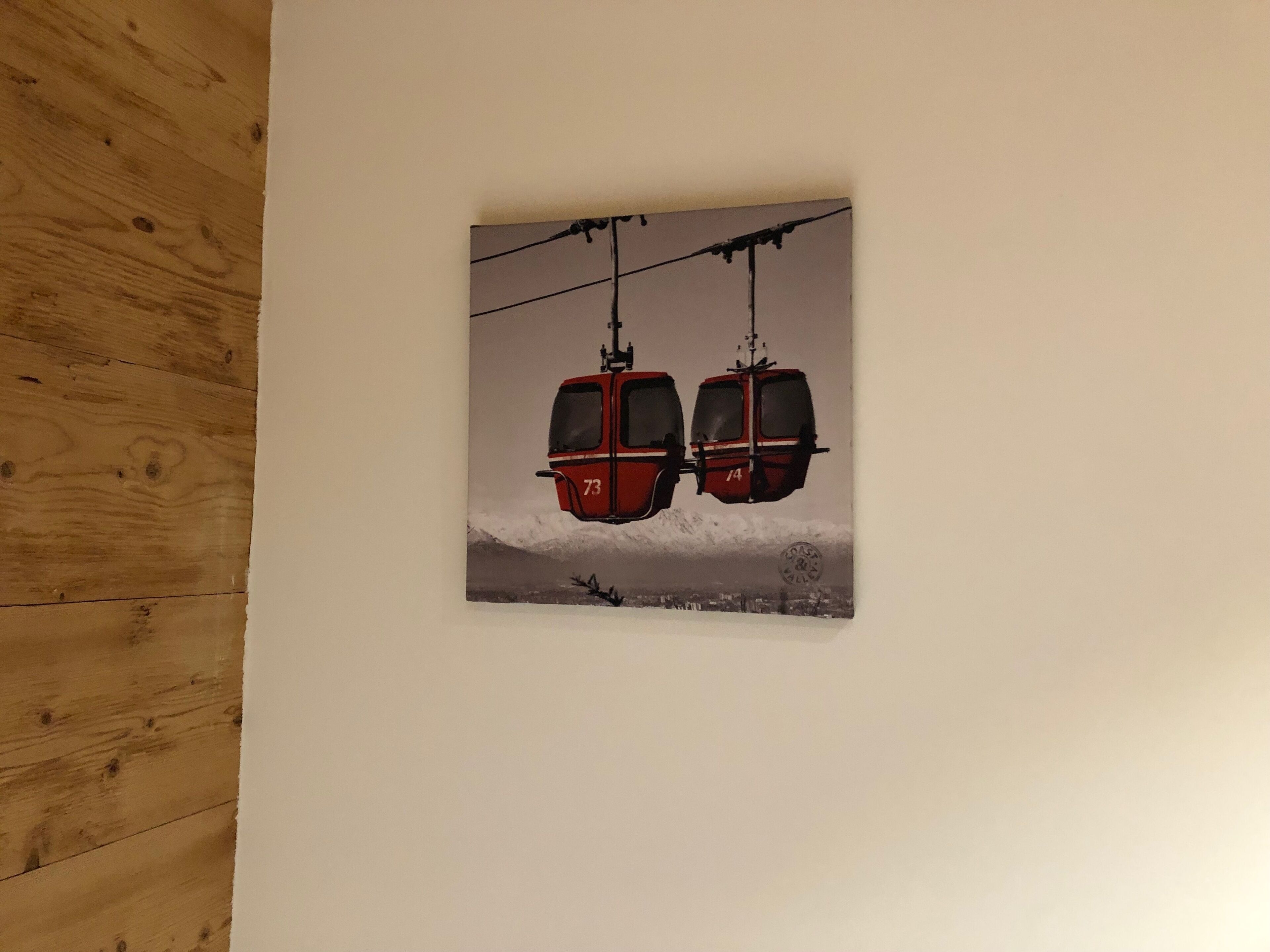 Fotografía de dos funiculares rojos, con los números 73 y 74, suspendidos por cables frente a un paisaje montañoso nevado.