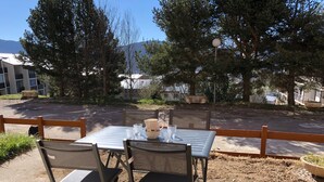 An outdoor patio with a metal table and chairs, surrounded by a wooden fence. - BEAUTIFUL T3 ESPRIT CHALET (LES ANGLES)