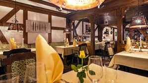 A restaurant interior with wooden beams, tables set with yellow napkins, and hanging lanterns. - Vacation apartment "Katarina 1", right next to Landhotel Albers - your landlords  (Schmallenberg)