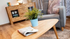 A living room with a wooden coffee table, a potted plant, and a newspaper. - Vacation apartment "Katarina 1", right next to Landhotel Albers - your landlords  (Schmallenberg)