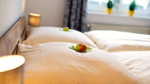 A hotel room with two beds, each with a pillow and a single apple on a green leaf. - Vacation apartment "Katarina 1", right next to Landhotel Albers - your landlords  (Schmallenberg)
