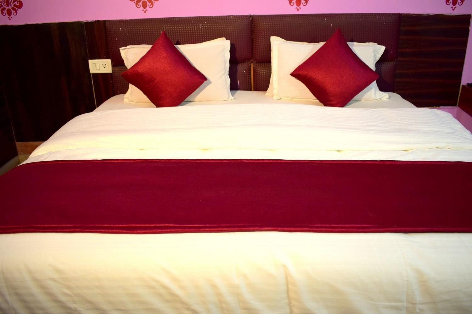 A bed with a white and red bedspread, two red pillows, and a dark headboard.