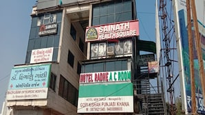 A building with multiple signs, including "Sainath Health Square" and "Hotel Ramhe A C Room". - Hotel Radhe (Vadodara)