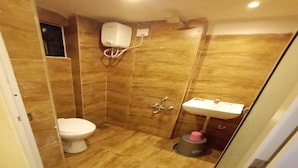 A small bathroom with a toilet, a sink, and a shower. - Hotel Radhe (Vadodara)