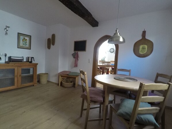 Een eethoek met een ronde tafel, houten stoelen en een hanglamp.