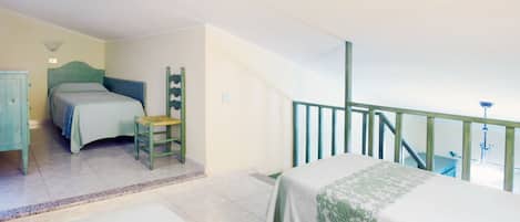 A bedroom with a bed, a chair, a dresser, and a staircase.
