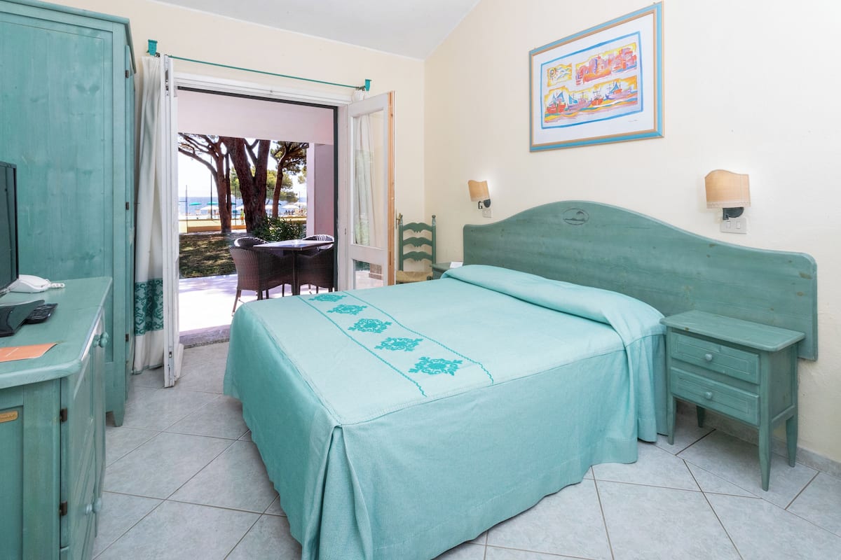 A room with a bed, a desk, a chair, a nightstand, and a painting on the wall.
