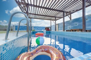 Une piscine dotée d’une zone couverte, d’un plongeoir et de jeux gonflables.