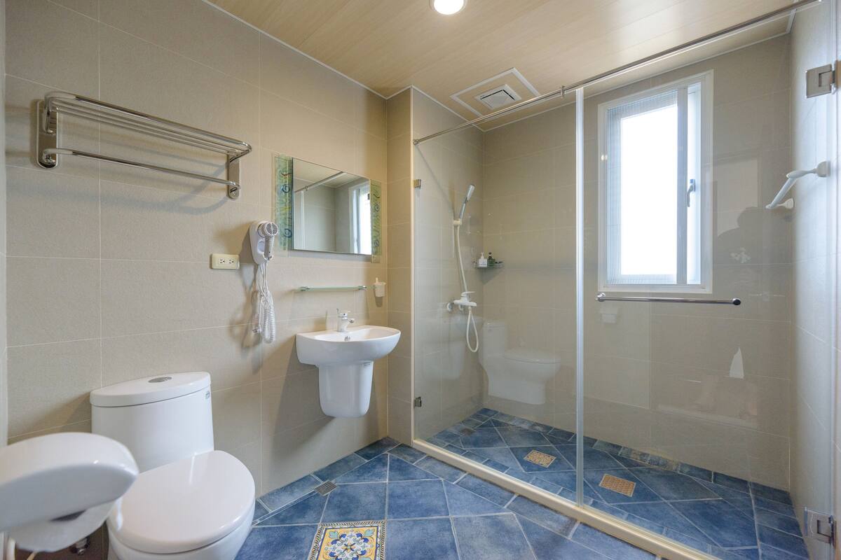 A bathroom with a toilet, sink, and glass shower enclosure.