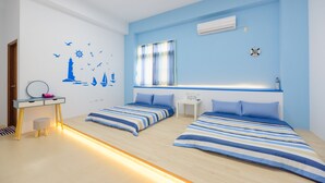 A room with two beds, a desk, and a window with curtains.