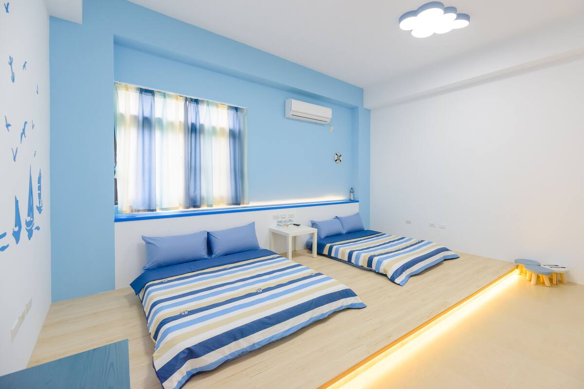 Una habitación con dos camas, una mesita y una ventana con cortinas.