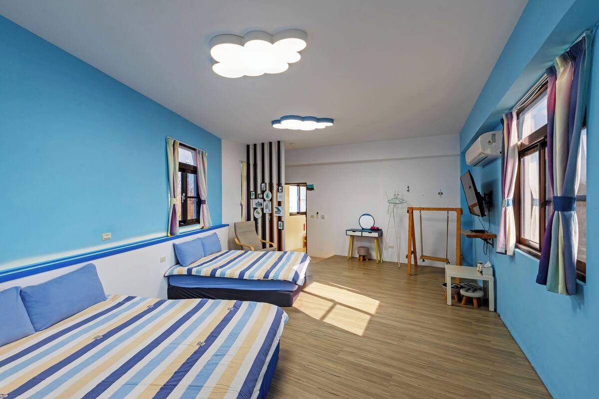 Una habitación con dos camas, un escritorio, una silla, un espejo y una ventana con cortinas.
