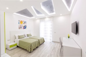 Un dormitorio moderno con cama, mesitas de noche, un escritorio y televisor.