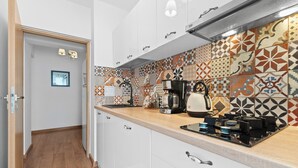 Une cuisine moderne avec des armoires blanches, un plan de travail en bois et un revêtement mural décoratif.