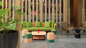 Un espace extérieur moderne aménagé avec un canapé vert, des chaises en bois et une table.