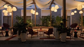 Un espace de détente intérieur moderne, agrémenté de luminaires suspendus, de sièges confortables et de plantes en pot.